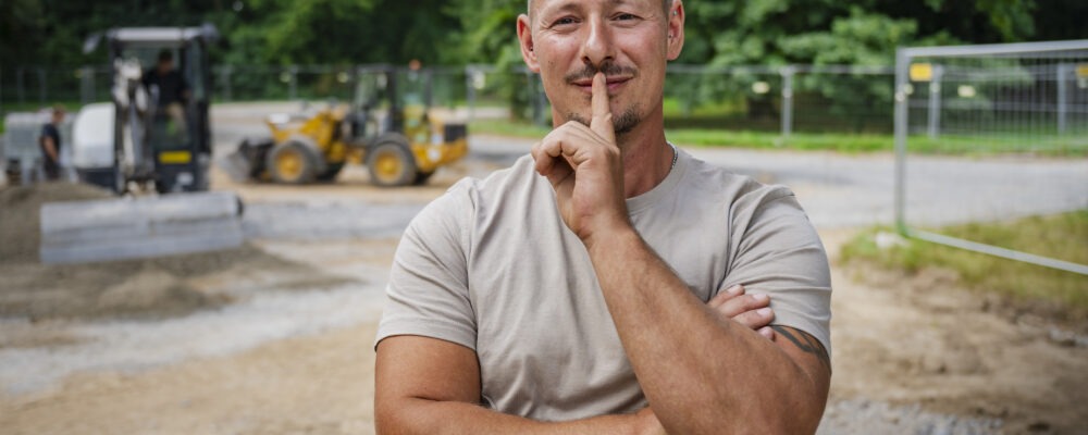 Baustellenleiter auf der Baustelle und schaut in die Kamera.