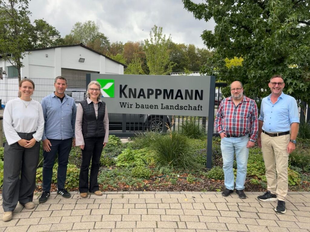 Stolzes Gruppenbild vor dem Firmenschild anlässlich der erfolgreichen AMS Rezertifizierung.
