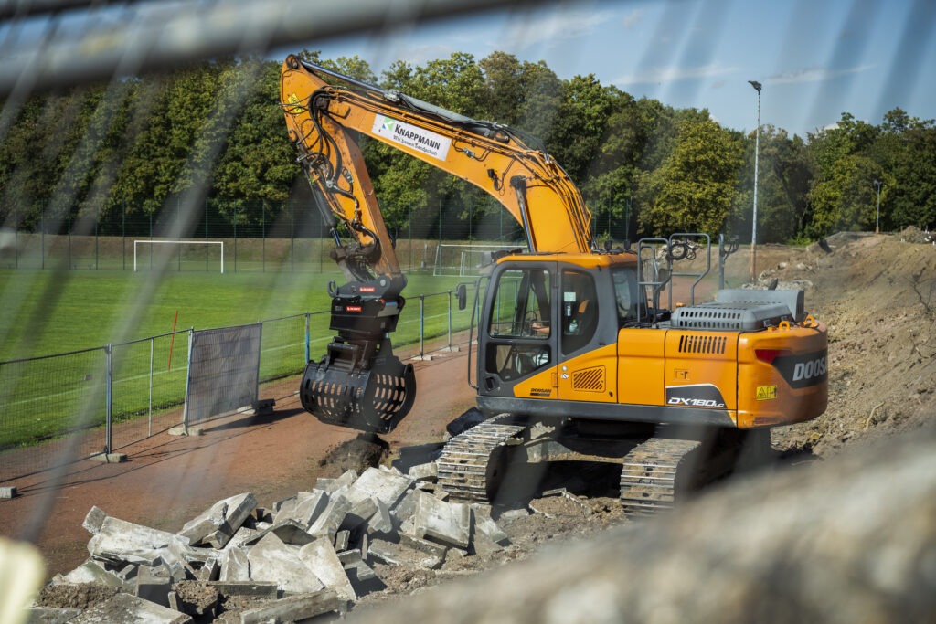 Bagger beim Abbruch der alten Stehstufenanlage im Südstadion Gelsenkirchen-Ückendorf. KNAPPMANN führt die Rückbauarbeiten als Teil der Neugestaltung der Sportanlage durch.