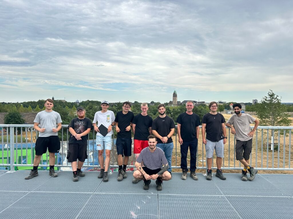 Gruppenfoto der neuen Azubis mit Ausbilder Nils Oechler beim Projekt Hochfeldallee im Rheinpark in Duisburg