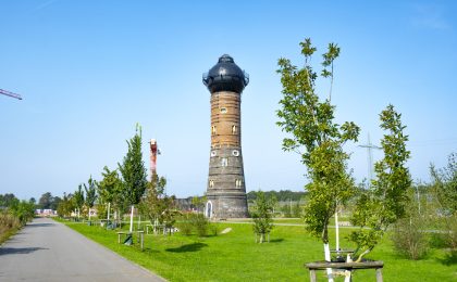 6-Seen-Wedau in Duisburg. Auf dem Bild ist der Wasserturm zu sehen, sowie viele Bäume und Wiese.