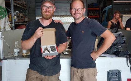 Oliver Füchtenbusch (links) gratuliert Maximilian Kirschke (rechts) zum bestandenen Meister. Sie schauen lächelnd in die Kamera.