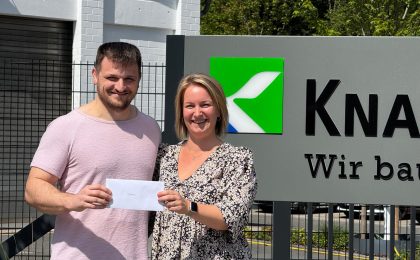 Laura Knappmann übergibt Durim Vladi einen Umschlag zur bestandenen Prüfung.