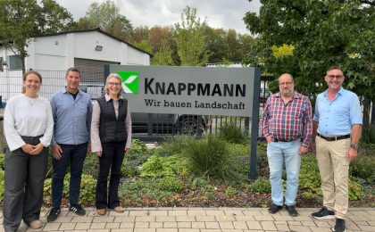 Stolzes Gruppenbild vor dem Firmenschild anlässlich der erfolgreichen AMS Rezertifizierung.